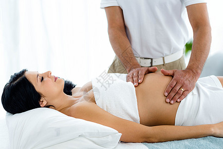 从按摩师那里接受胃部按摩的孕妇女性闲暇保健孕产水疗生活方式美容腹部护理女士图片