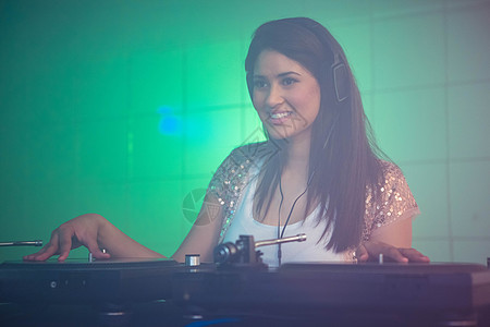 美丽的女性DJ玩音乐夜生活转盘夜店混合器光盘表演微笑记录享受大碟图片