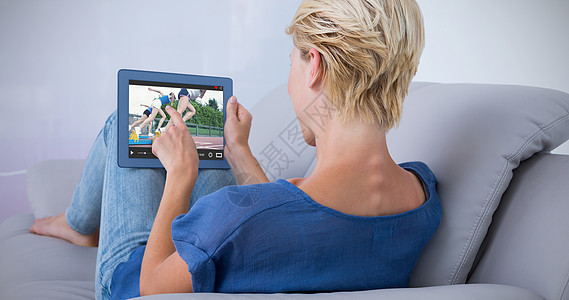 金发女人在沙发上使用平板石的复合图像滚动科技竞技休闲运动员赛跑者电脑赛车微笑训练图片