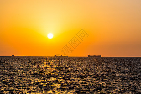 日落背景大型船舶反射海洋海浪海滩天空红色地平线太阳橙子黄色图片