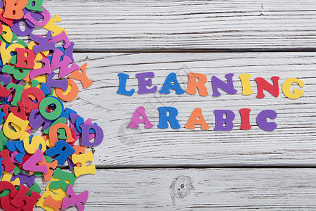 在白木板上用多彩的字母 以阿拉伯语写成标签写作刻字打字稿网络艺术凸版字体拼写积木图片