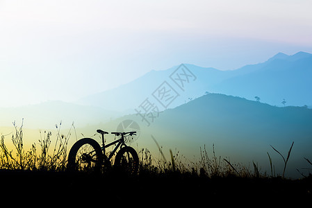 美丽的日落天空和山地自行车的轮廓 轮椅肥脚踏车旅行骑士活动车轮场地太阳日出闲暇天空运动图片