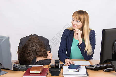 办公室里的情况——沮丧的女人躺在桌子上 她的同事傲慢地看着她图片