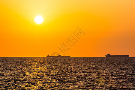 日落背景大型船舶海滩阳光海浪红色橙子反射黄色天空海洋地平线图片
