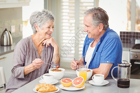 快乐的老年情侣在吃早餐时讨论图片