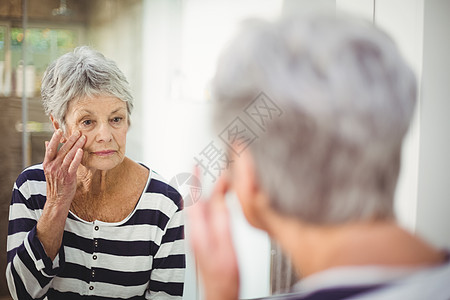 照镜子看皮肤的老年妇女的反射情况背景图片