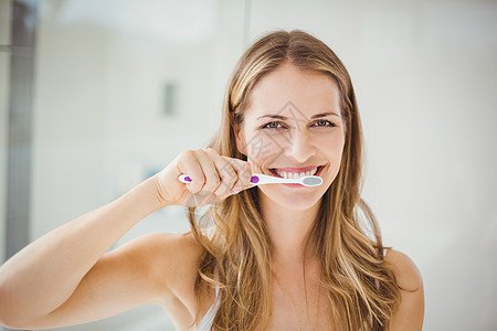 青年妇女刷牙浴室长发微笑女性浅色口腔打扫医疗健康牙刷图片