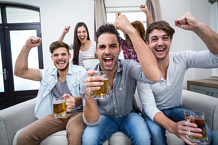 朋友在看足球赛时欢呼和喝酒 并饮酒图片