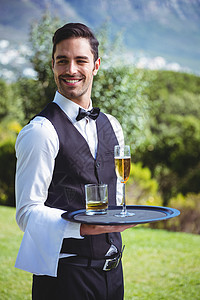 英俊的侍应服务员拿着托盘端着饮料服务冰块酒店工作行业长笛酒精玻璃男性男人图片