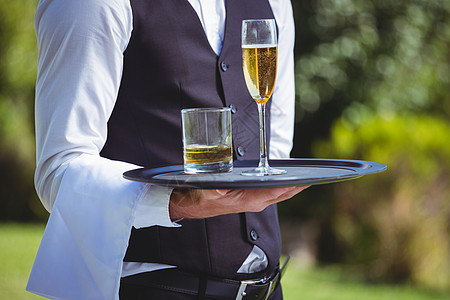 英俊的侍应服务员拿着托盘端着饮料男性玻璃冰块太阳命令酒精长笛晴天食品行业图片
