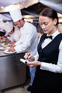 商业厨房有便条垫的服务员台面合作男性餐饮职业命令制服工作同事服务器图片