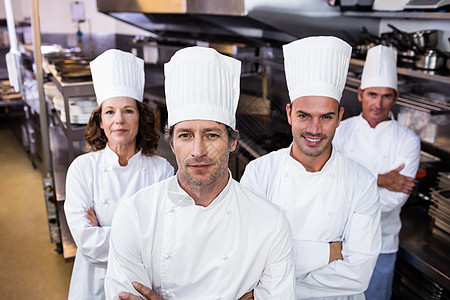 一群快乐的厨师对着镜头微笑制服厨艺男性女士厨房白人女性商业酒店职员图片