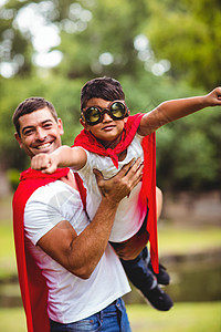 父亲和儿子假扮超级英雄斗篷红毯子英雄享受家庭飞行男人混血拳头娱乐背景图片