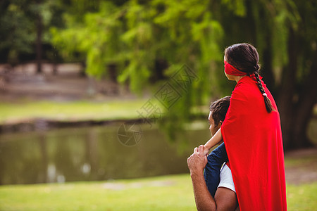 穿着超级超级英雄服装的女孩坐在父亲肩上喜悦超级英雄女儿面具娱乐斗篷混血乐趣孩子英雄图片