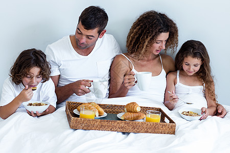 家庭在床上吃早餐男生女孩闲暇女士混血卧室父亲托盘公寓茶杯图片