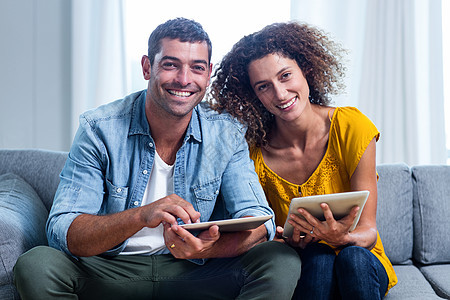 坐在沙发上并使用数字平板电脑的肖像年轻夫妇互联网感情技术触摸屏房子男性女士快乐乐趣网络图片