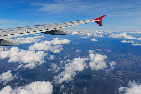 从一架飞机的窗口看到美丽的云天和机翼 其景象如下运输地球航天旅行白色航班土地蓝色商业假期图片