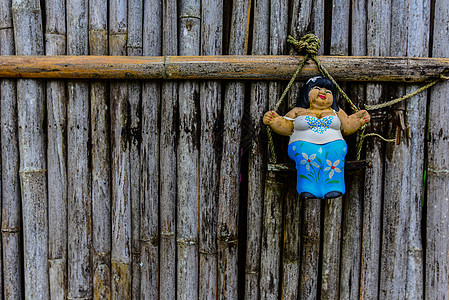 女性克莱雕塑挂在旧竹子门前图片