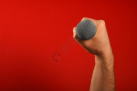 男子用麦克风在红色背景上牵手拳头记录音乐嗓音男人音乐家歌手展示工作室演出背景图片