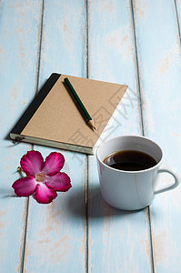 一杯咖啡 笔记本 铅笔和粉红色花 在天空蓝色木地板上图片