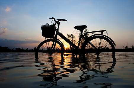 日落时站立在水中旅行美丽运动女性镜子场地自行车孩子天空女士图片