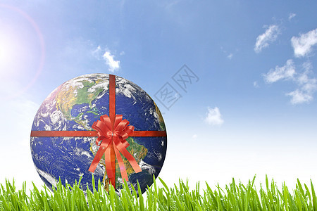 地球 在阳光明媚的美丽绿草上带红丝带图片