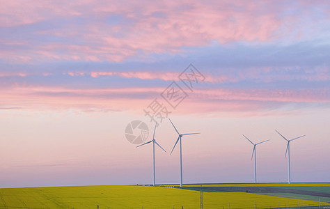 日落时尤利安油田和风力涡轮机图片