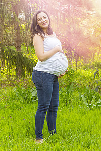 温暖的夏日户外怀孕年轻女子肖像场地母性裙子父母太阳腹部生育力生活女孩婴儿图片