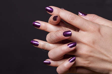 紧贴女性的手 在黑色上指甲指甲油紫色阴影治疗虚荣女士化妆品美容师美甲图片