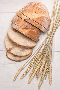 木制背景的新鲜自制面包和小麦图片