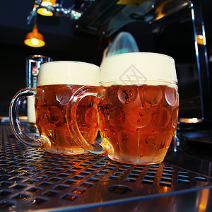 酒吧桌上的大啤酒杯金子啤酒厂白色玻璃液体生活桌子酒精黄色饮料图片
