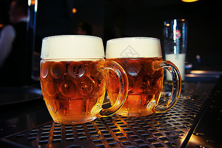 酒吧桌上的大啤酒杯桌子液体泡沫饮料金子啤酒白色玻璃黄色酒精图片