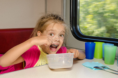 火车上的女孩坐在汽车二等舱车厢下层的一张桌子上 用甜汤匙吃着这个餐桌图片
