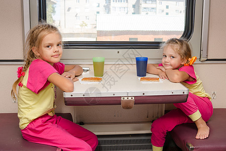 火车上的两个小女孩穿着同样的衣服坐在外二等车厢的桌子旁图片