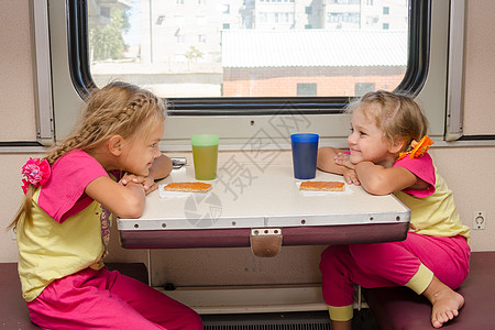 火车上坐在二等车厢外的桌子旁 两个笑脸相视的小女孩图片