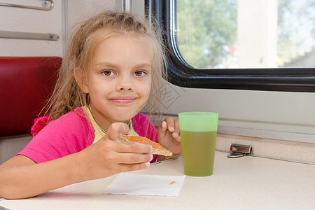 6岁女孩喝茶 在火车上吃三明治 在二等车外的餐桌前喝茶图片