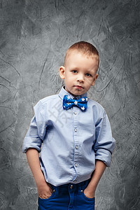 穿着牛仔裤 蓝衬衫和领结的可爱男孩肖像口袋快乐理发配件婴儿青年蓝色时尚学校童年图片