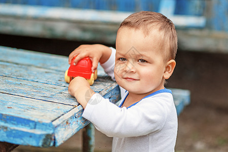 美丽的棕色眼睛小男孩玩着红色塑料玩具c图片