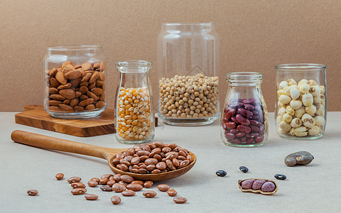棕色背景的玻璃杯中各种豆子和坚果纤维小吃勺子豆类美食粮食花生黄油营养奶制品图片