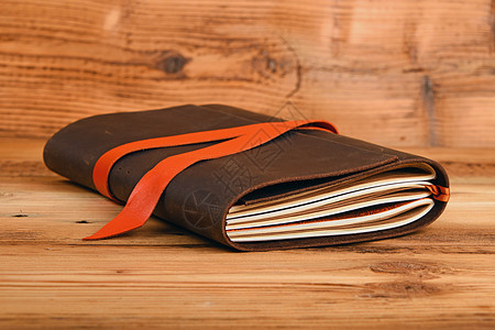 木制桌上皮革封面笔记本回忆书签桌子棕色笔记木头写作软垫药片记事本图片