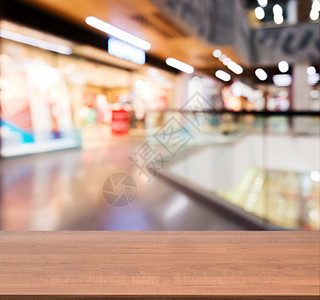 金色大厅在模糊商场前面的木板空桌背景购物中心木头中心台面走廊商业店铺展示架子背景