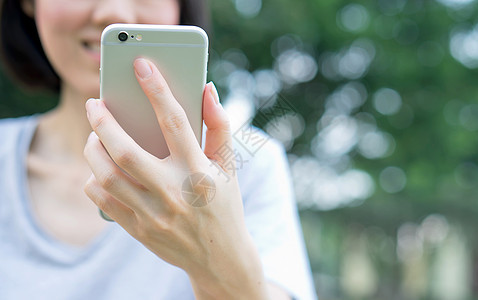妇女在公园里使用移动智能手机技术绿色工具冲浪手指女士电脑电话女孩细胞图片