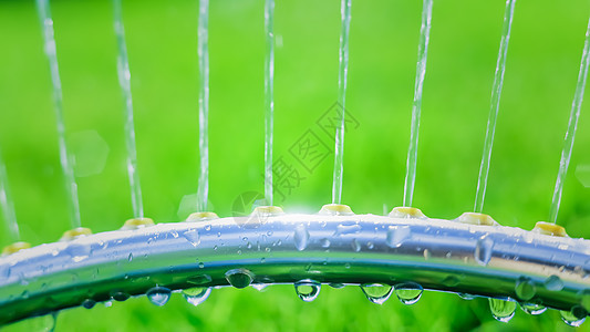 草坪喷洒机在绿草上浇水淋浴院子晴天背光水分技术园艺喷射管道工具图片