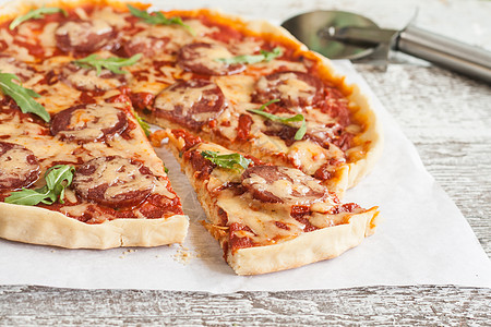 披萨和披萨刀土制披萨 配有腊肠 西红柿和草药洋葱草本植物温度香菜厨房工作室食物美食文化叶子背景