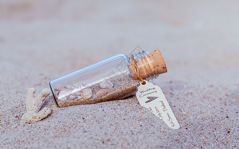 在热带沙滩上 贴上一瓶有海壳和纸牌标签的婚礼邀请信箱图片