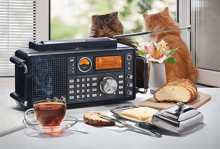 热茶 面包和油 放在桌子上 无线电收音机对着一个开着的窗口勺子美食油炸窗户白色早餐营养甜点木头黄色图片
