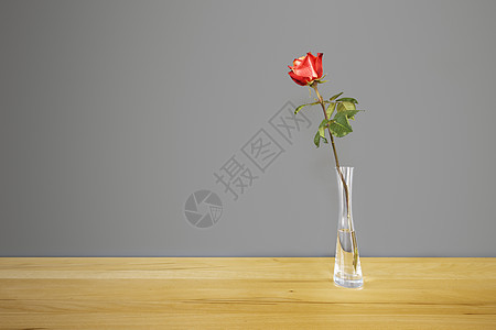 红玫瑰在灰墙前桌子叶子花瓶玻璃植物庆典礼物浪漫花瓣图片
