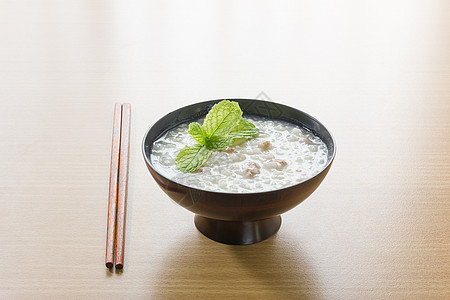 碗中传统中国大米粥美食麦片食物文化稀饭猪肉早餐筷子白色桌子背景图片