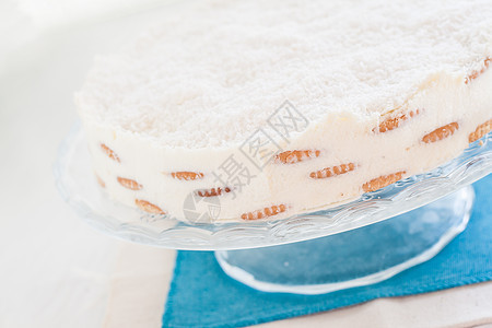 蓝毛巾上的椰子蛋糕糕饼蓝色糕点地区文化美食可可摄影奶油木头勺子背景图片