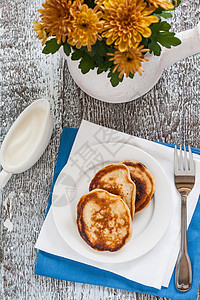 木制桌上有糖浆 果酱和鲜花的煎饼温度蓝色文化油炸早餐烹饪小吃桌子美食木头图片